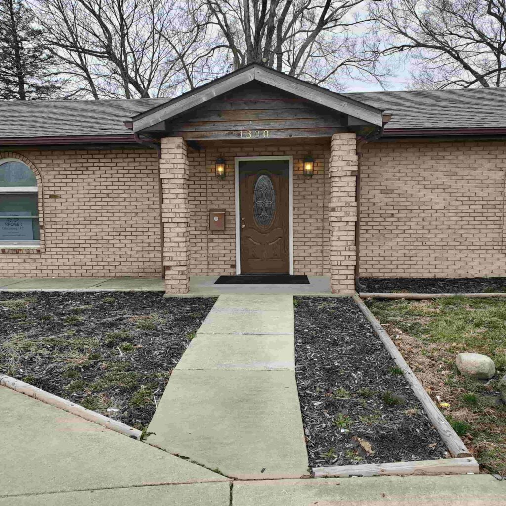 A house with a sidewalk and trees in the background