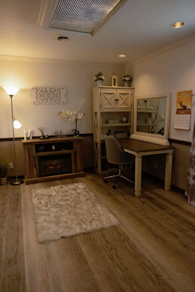 A room with a desk, chair and television.