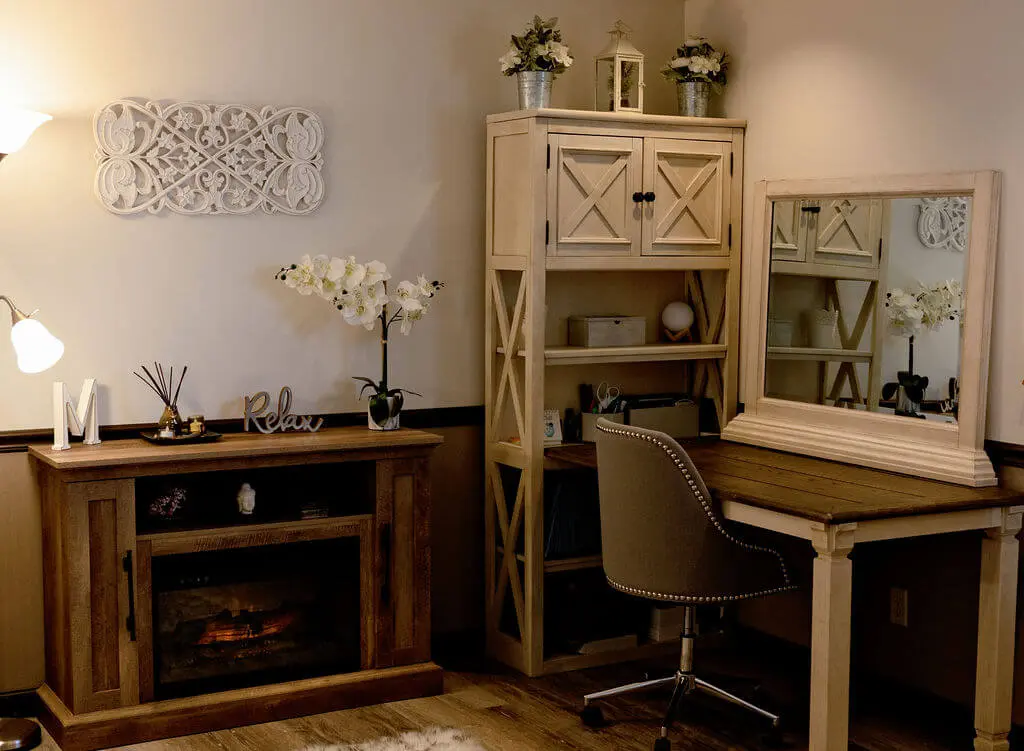 A room with a desk and chair, fireplace and mirror.