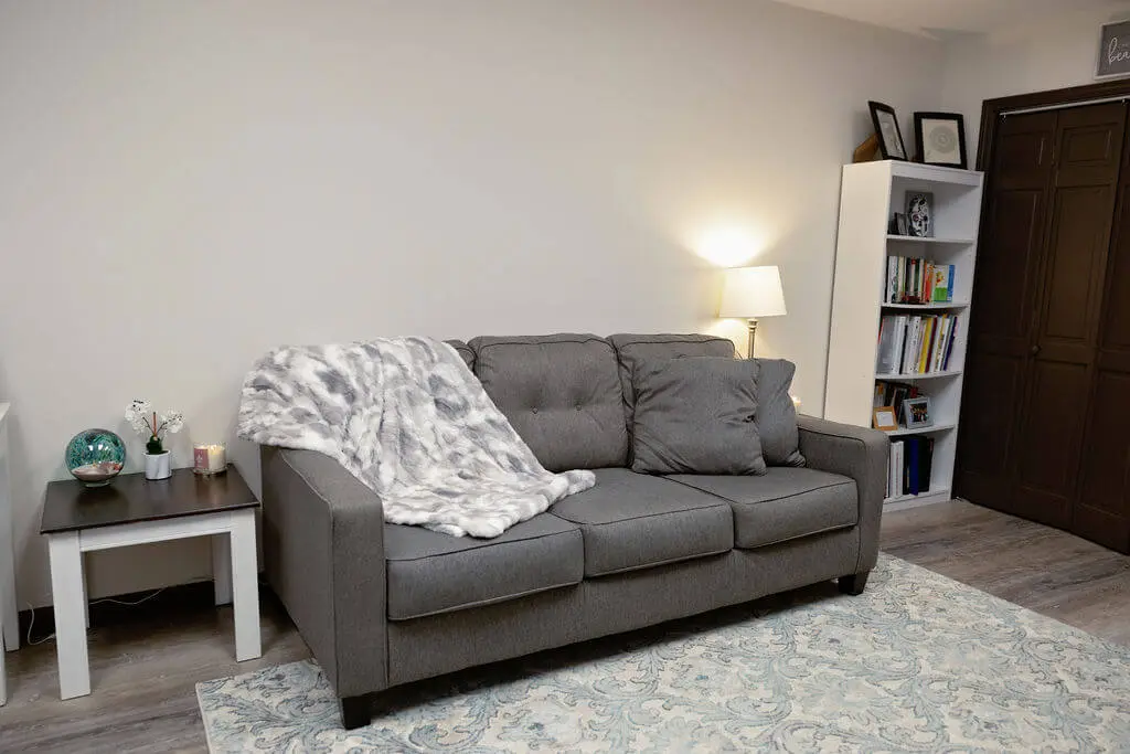 A gray couch in front of a white wall.