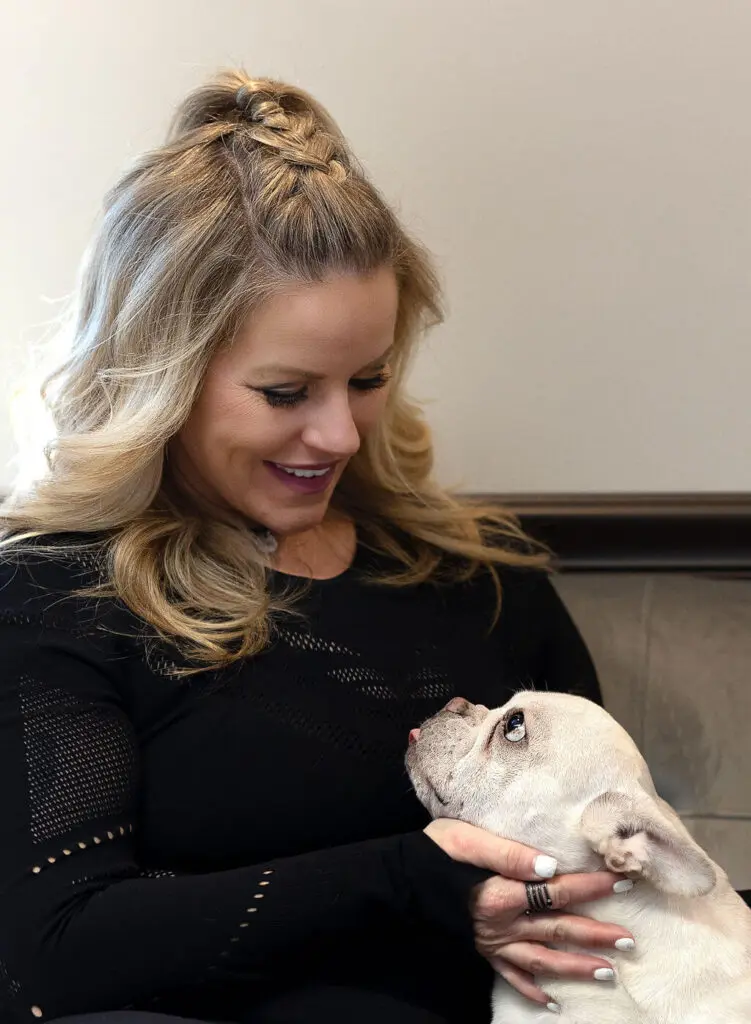 A woman holding a white dog on her lap.